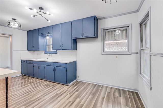 kitchen featuring light hardwood / wood-style floors, a notable chandelier, blue cabinets, ornamental molding, and sink