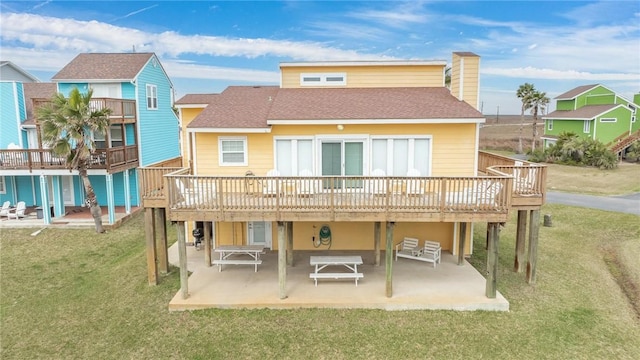 back of house featuring a patio, a shingled roof, a lawn, and a wooden deck