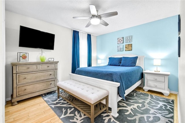 bedroom with ceiling fan, a textured ceiling, and wood finished floors