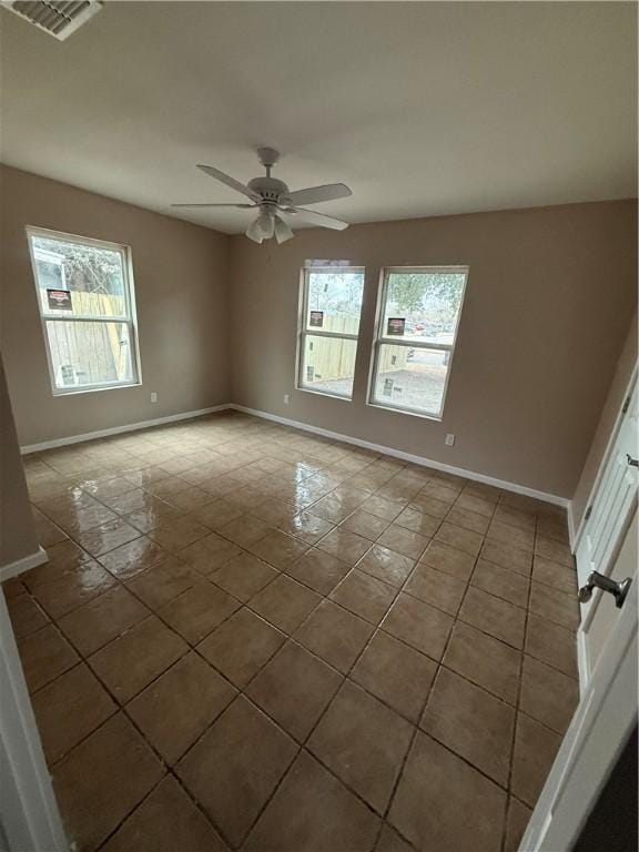 tiled empty room featuring ceiling fan