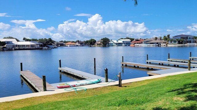 view of dock with a residential view, a water view, and a yard