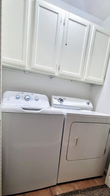 clothes washing area with wood finished floors, washing machine and clothes dryer, and cabinet space