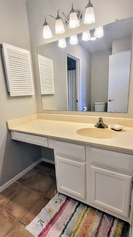 bathroom featuring toilet, tile patterned floors, vanity, and baseboards