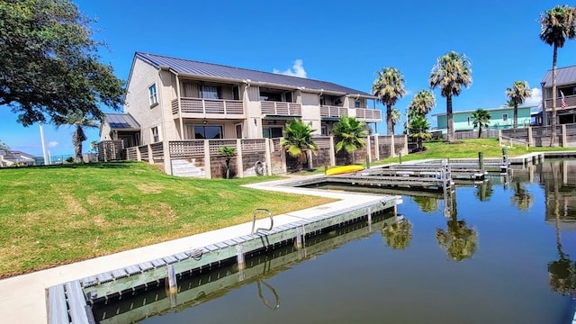 view of dock with a lawn and a water view