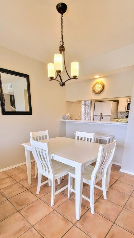 dining room featuring light tile patterned floors, baseboards, and a notable chandelier