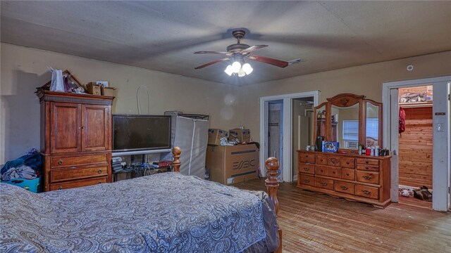 bedroom featuring light wood-type flooring, wooden walls, and ceiling fan