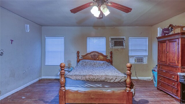 bedroom featuring cooling unit, a wall unit AC, hardwood / wood-style flooring, and ceiling fan