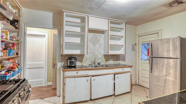 kitchen with light tile patterned flooring, sink, appliances with stainless steel finishes, white cabinets, and decorative backsplash