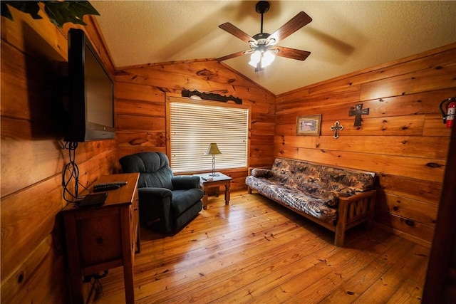 living room with vaulted ceiling, a textured ceiling, ceiling fan, and light hardwood / wood-style flooring