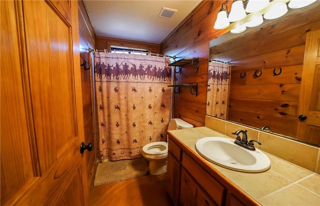 bathroom with toilet, wooden walls, walk in shower, and vanity