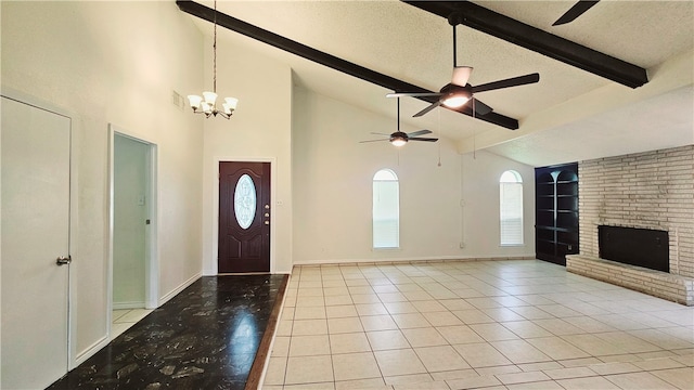 foyer entrance featuring light tile patterned flooring, a fireplace, a textured ceiling, a notable chandelier, and beam ceiling