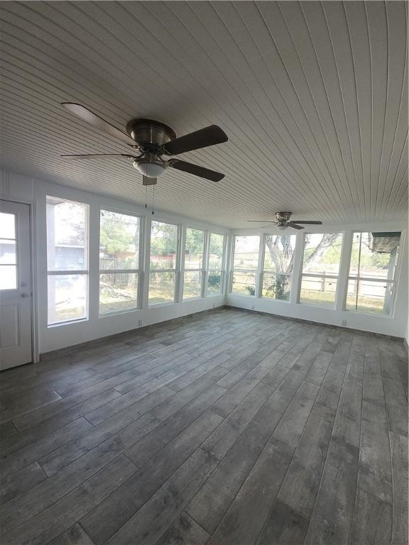 unfurnished sunroom with ceiling fan, a healthy amount of sunlight, and wood ceiling