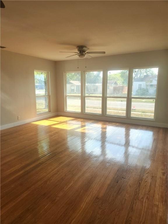 unfurnished room with a wealth of natural light, hardwood / wood-style floors, and ceiling fan