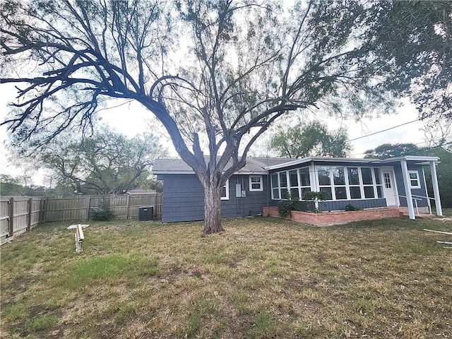 rear view of property with a sunroom, cooling unit, and a lawn