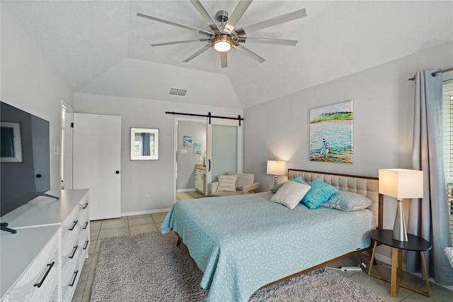 bedroom featuring a barn door, light tile patterned floors, lofted ceiling, ceiling fan, and ensuite bathroom