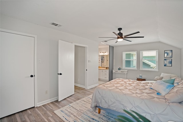 bedroom featuring light wood-type flooring, vaulted ceiling, ceiling fan, and ensuite bathroom