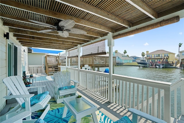 balcony with a deck with water view, ceiling fan, and a boat dock