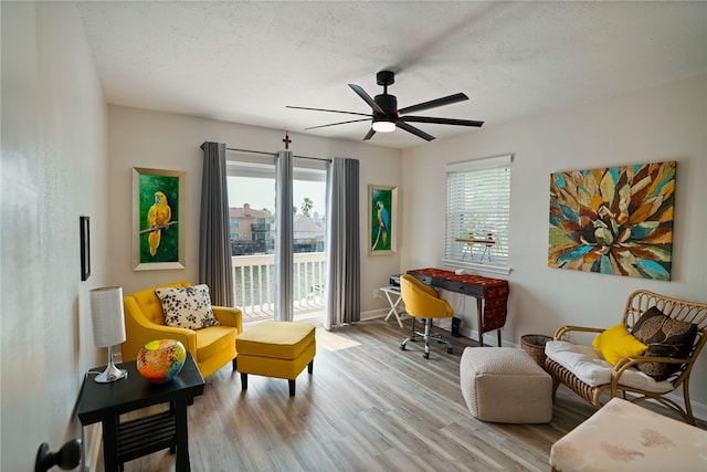 sitting room featuring light wood-type flooring, a textured ceiling, and ceiling fan