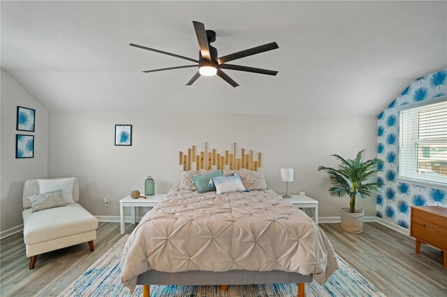 bedroom featuring ceiling fan, light hardwood / wood-style flooring, and lofted ceiling