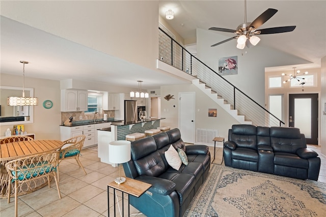 tiled living room with a high ceiling, ceiling fan with notable chandelier, a healthy amount of sunlight, and sink