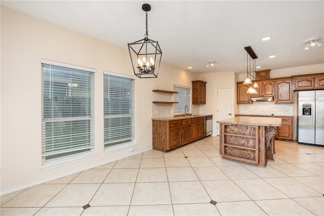 kitchen with a kitchen island, a notable chandelier, light tile patterned floors, stainless steel refrigerator with ice dispenser, and hanging light fixtures