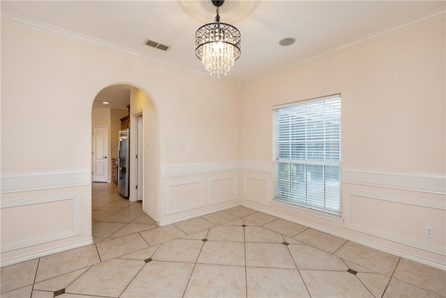 spare room featuring a notable chandelier, light tile patterned floors, and ornamental molding