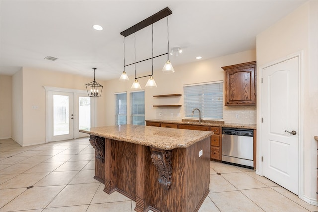 kitchen featuring light stone counters, a kitchen island, hanging light fixtures, sink, and stainless steel dishwasher