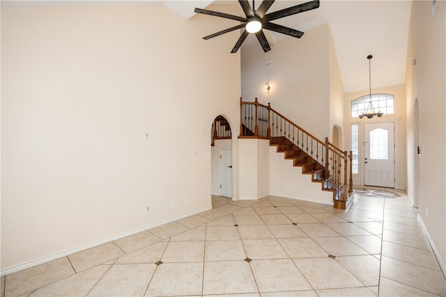 tiled foyer with high vaulted ceiling and ceiling fan with notable chandelier