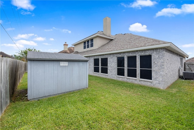 rear view of property featuring central AC unit, a shed, and a lawn