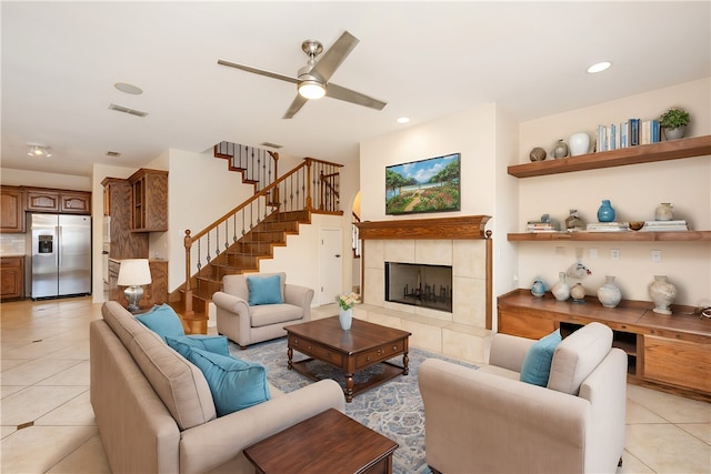 living room featuring light tile patterned flooring, ceiling fan, and a tile fireplace