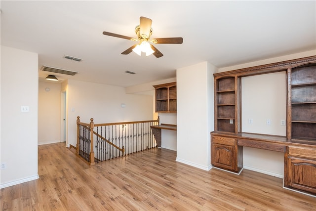 spare room with ceiling fan, built in desk, and light hardwood / wood-style floors