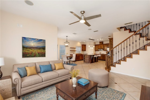 tiled living room with ceiling fan with notable chandelier