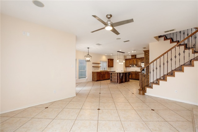 unfurnished living room with ceiling fan with notable chandelier and light tile patterned floors