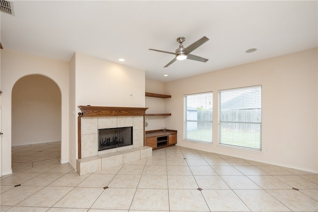 unfurnished living room featuring ceiling fan, a tile fireplace, and light tile patterned floors