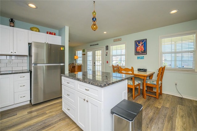 kitchen with stainless steel fridge, white cabinetry, hardwood / wood-style floors, and backsplash