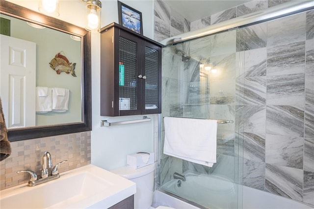 full bathroom featuring vanity, bath / shower combo with glass door, tasteful backsplash, and toilet