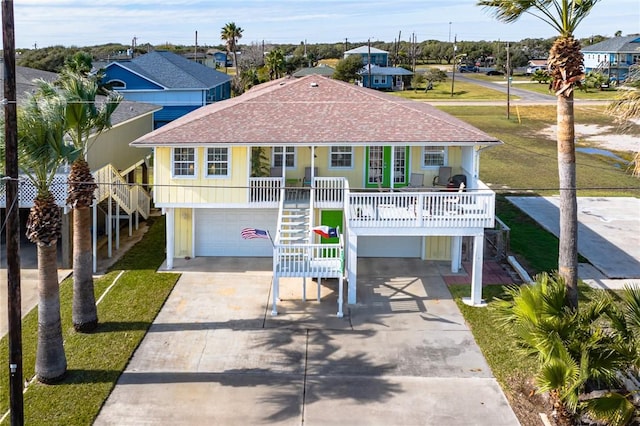 raised beach house featuring covered porch and a garage