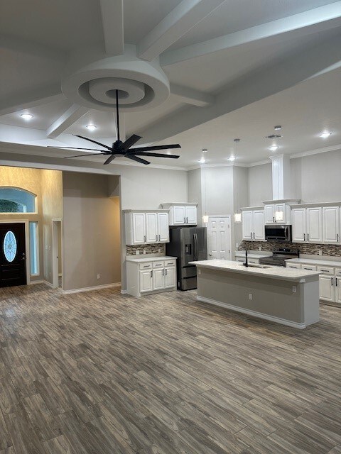 kitchen with stainless steel appliances, dark hardwood / wood-style floors, backsplash, an island with sink, and white cabinets