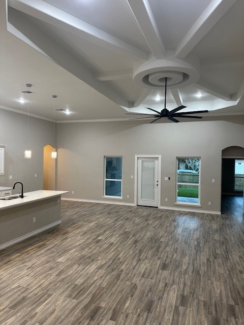 unfurnished living room featuring beam ceiling, ceiling fan, sink, and dark hardwood / wood-style floors