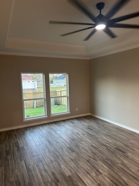 unfurnished room featuring a raised ceiling, ceiling fan, dark hardwood / wood-style flooring, and ornamental molding