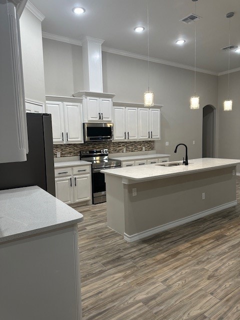 kitchen featuring white cabinetry, sink, an island with sink, pendant lighting, and appliances with stainless steel finishes