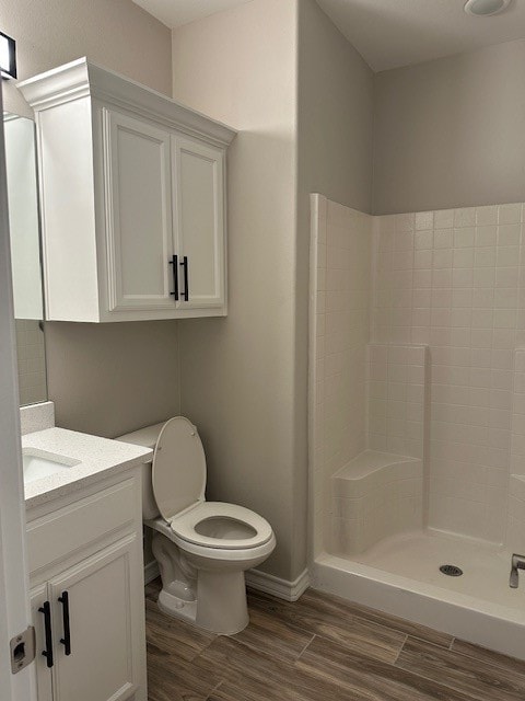 bathroom with hardwood / wood-style floors, vanity, toilet, and walk in shower