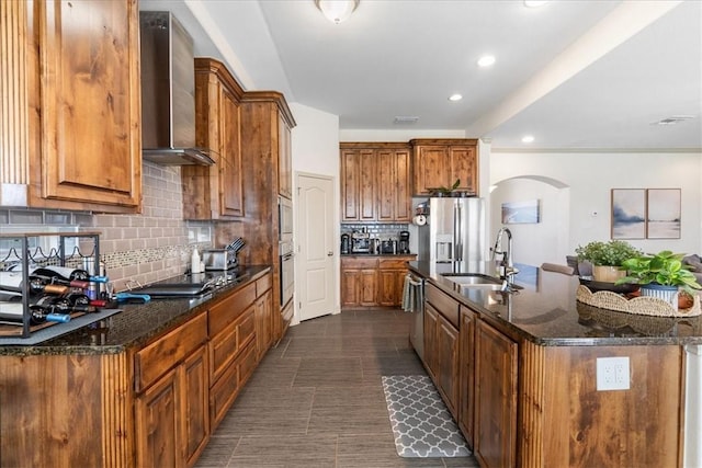 1805 Bay Landing Dr, Portland, TX 78374 - kitchen featuring wall chimney exhaust hood, arched walkways, appliances with stainless steel finishes, a kitchen island with sink, and tasteful backsplash