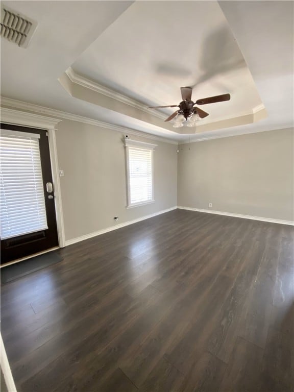 spare room with a raised ceiling, ceiling fan, dark hardwood / wood-style flooring, and ornamental molding