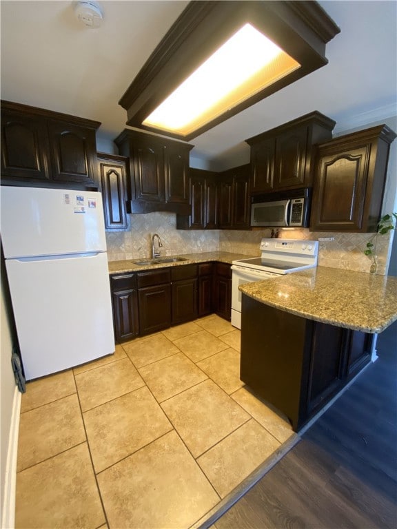 kitchen with kitchen peninsula, backsplash, white appliances, crown molding, and sink