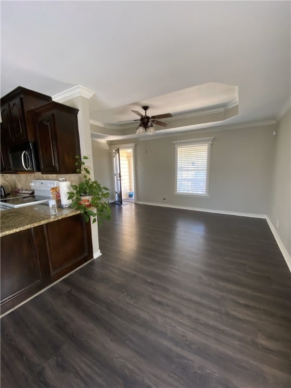 kitchen with dark brown cabinetry, dark wood-type flooring, a raised ceiling, crown molding, and stove