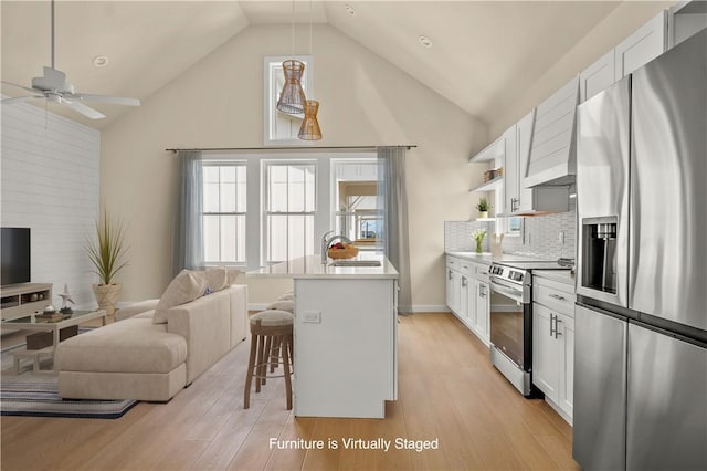 kitchen with open floor plan, a breakfast bar, stainless steel appliances, a ceiling fan, and a sink