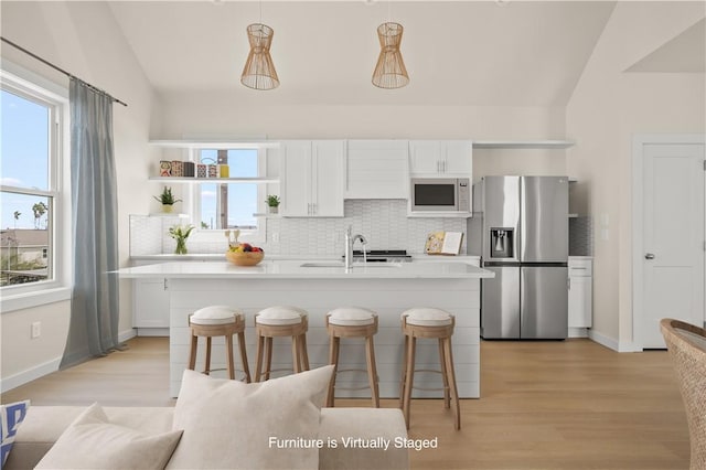 kitchen with tasteful backsplash, light countertops, lofted ceiling, stainless steel fridge, and white cabinetry