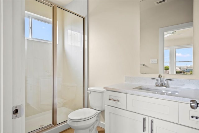 full bathroom with vanity, a ceiling fan, visible vents, a shower stall, and toilet