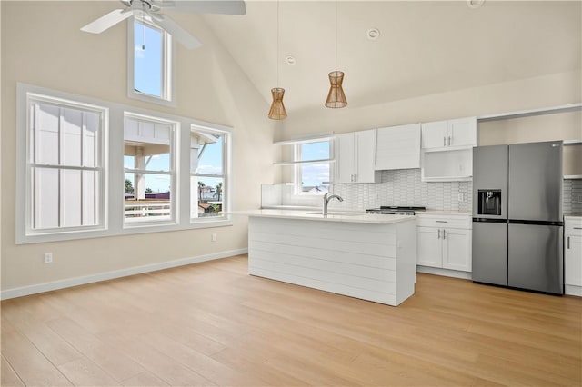 kitchen featuring backsplash, light countertops, light wood-style floors, stainless steel refrigerator with ice dispenser, and white cabinets